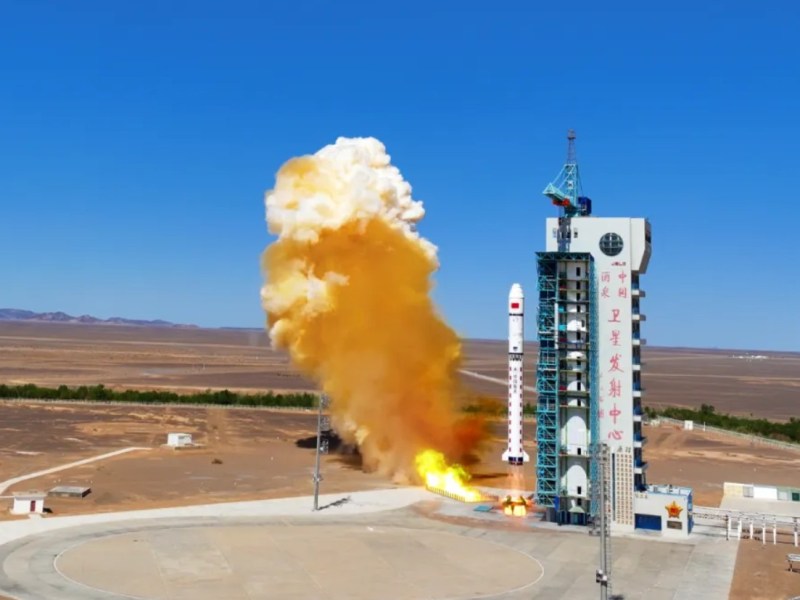 A Long March 2D rocket lifts off from Jiuquan Satellite Launch Center in northwest China, trailing bright yellow-orange exhaust against a clear blue sky, carrying the CSES-2 (Zhangheng-2) satellite on June 14, 2025