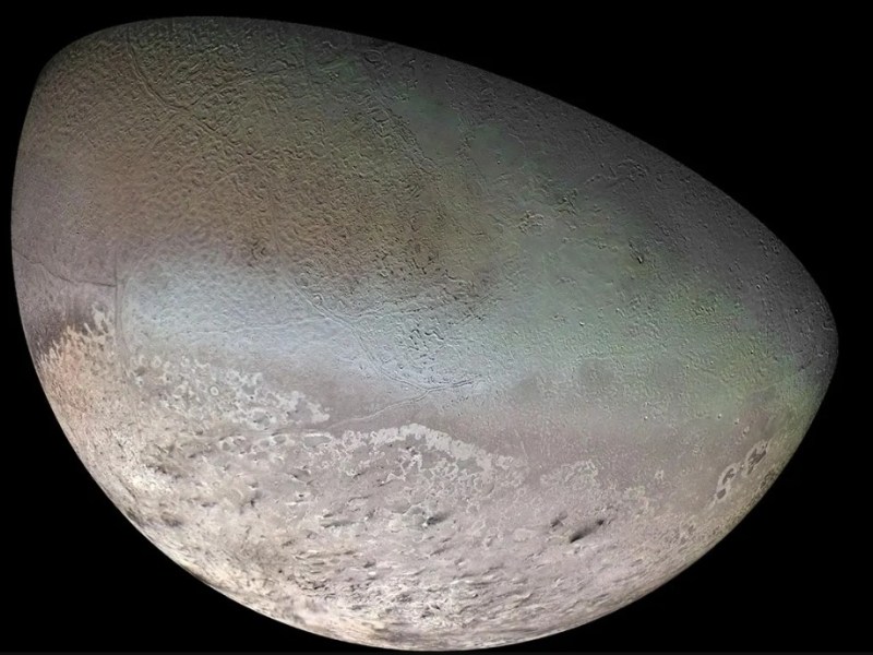 Enhanced image of Neptune’s moon Triton captured by NASA’s Voyager 2 spacecraft, showing a crescent-shaped, geologically complex surface with icy plains, ridges, and faint greenish and reddish hues.
